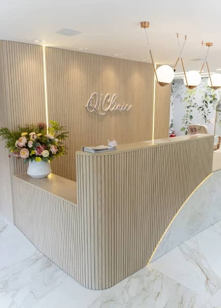 Recepção da Q!Clinic com balcão ripado, letreiro e flores